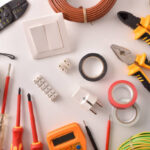 Tools and electrical material on a white table general view Horizontal composition. Top view.